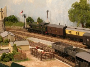 Syd 125. Operating a model railway. Prairie with horse box behind passes inner home signal and brings a local passenger train past Sheepcroft Yard into Hintock Redux. The horse box is destined for the Bay 